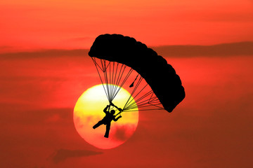  silhouettes parachuting on sunset