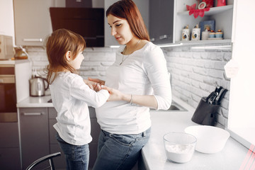Pregnant mother with a daughter. Family in a kitchen