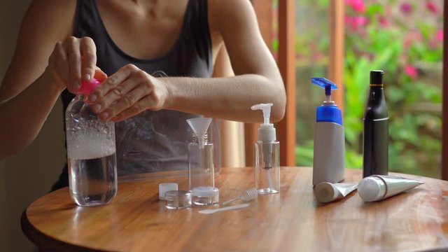 Young woman puts her cosmetics and shampoo in plastic bottles suitable for bringing onboard airplane. Travel kit for airplane. Travel concept