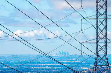 Los Angeles skyline behind power tower and power lines on a blue cloudy day - Powered by Adobe