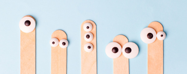 Wooden sticks for waxing hair, on blue background. spatula for sugaring with eyes, funny concept of...