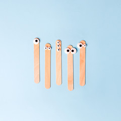 depilation, medical and beauty concept - wooden waxing spatula sticks with funny eyes on blue background, advertizing creative layout, minimal design, flyer, discount, sale