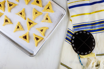 Uncooked jewish cookies on oven tray with kippa and tallit.