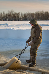 Naklejka premium Fitter with steel tongs pulls out ice block