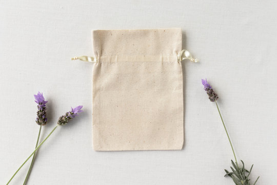 Blank Canvas Drawstring Bag On A Light Background With Lavender Flowers - Drawstring Bag Mockup Flat Lay