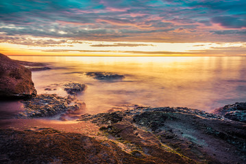 Fototapeta na wymiar Picturesque sunrise over a rocky beach.