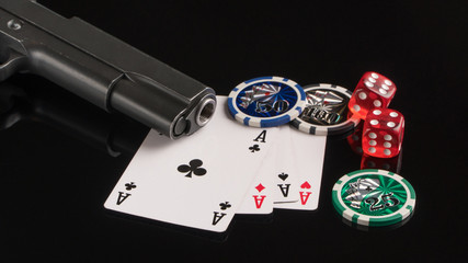 Poker chips, cards and a gun on a black background. The concept of gambling and entertainment. Casino and poker