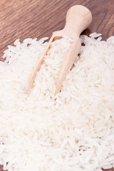 White rice and wooden scoop on rustic board