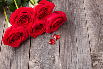 Red roses flowers and decorative hearts on gray wooden table. Greeting card. Copy space for text