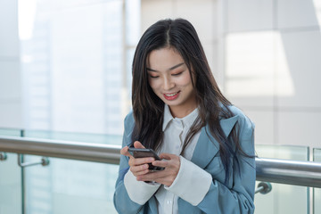 Business ladies use mobile phones in the corridor of office building