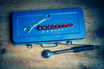 A wrench, a socket wrench and its inserts together with a blue tool box