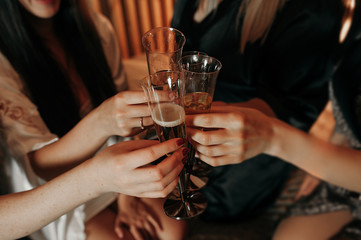 group of girls at a bachelorette party raise glasses of champagne with bubbles, light-skinned hands of girls, a hand with a wedding ring. warm tinting.