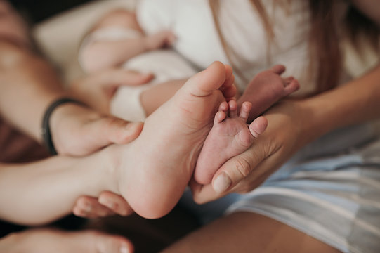 parents hold in their hands and compare their children's big and small feet, an image of legs of different sizes, an older child and a younger child