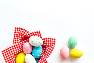 Easter eggs painted in basket on white desk top-down copy space