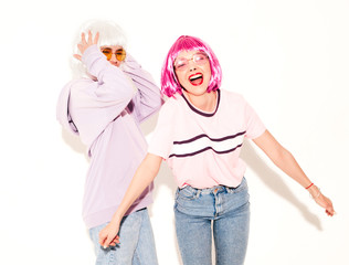 Two young sexy hipster girls in wigs and red lips.Beautiful trendy women in summer clothes.Carefree models isolated on white in studio.Positive female in sunglasses