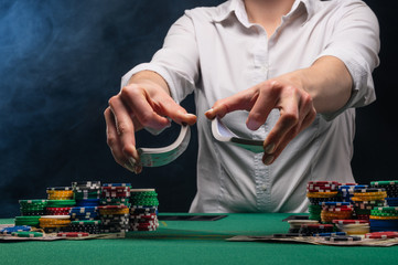 Girl dealer or croupier shuffles poker cards in a casino on the background of a table, chips,....