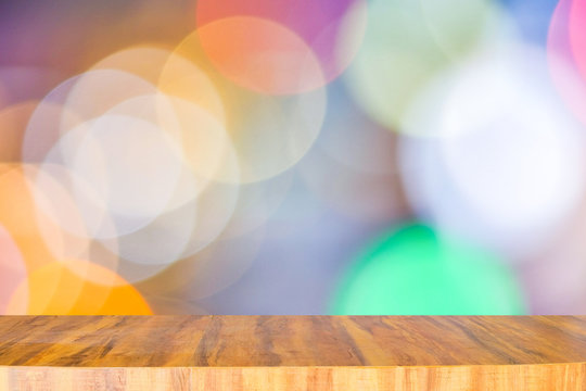 Empty long modern wooden counter on top for placing items and anything on blurred multicolored light bokeh background