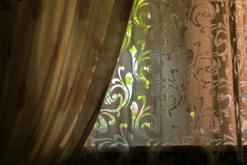 Home large and cozy window from which bright light passes into the room. Apartment fabric interior. Colored and transparent curtains with openwork pattern.