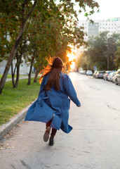 girl in stylish hipster outfit running and having fun. Exiting emotions. Autumn mood. Wearing gray sweater. Fashion.