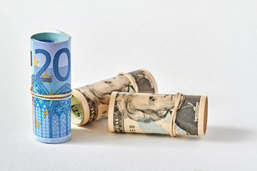Twenty Euro bill rolled up as a tubule stands on the background of twenty dollar bills. Concept of Euro superiority over dollar. Closeup, selective focus