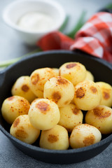 Close-up of roasted potato balls in a cast-iron frying pan, vertical shot, selective focus