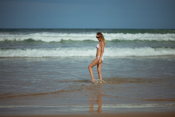 Young slim beautiful woman stay and posing in the sea or ocean waves