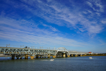 大きな川に架かる鉄橋と行きかう船　東京の荒川にて