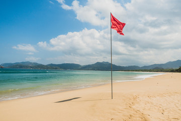 Red warning flag on a beautiful tropical empty beach of Indonesia