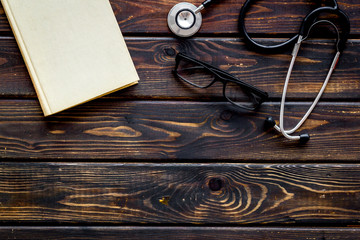 Medical books near stethoscope on dark wooden background top-down copy space
