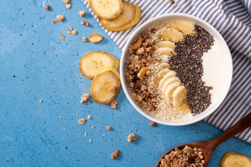 Healthy pineapple, mango smoothie bowl with coconut, bananas, blueberries and granola. Top view scene on a bright background.