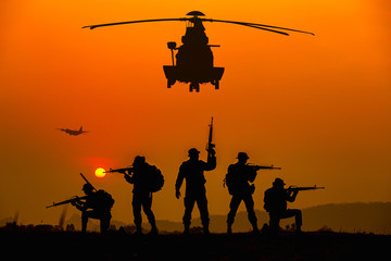 Silhouette of military rangers and Helicopter with soldier on the top of mountain at sunset