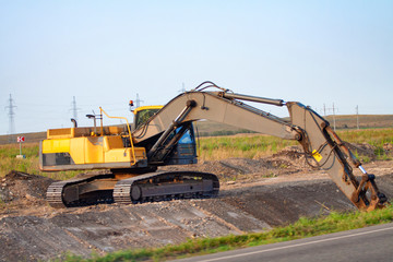 A large iron excavator bucket collects and pours sand rubble and stones in a quarry at the construction site of road facilities and houses