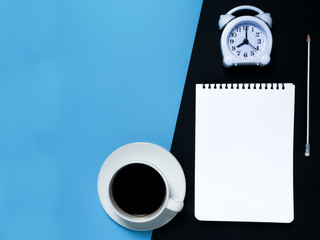 Obraz na płótnie Canvas Minimal black blue work space concept : Notepad , pencil , alarm clock, coffee, top view