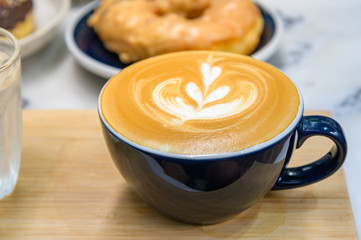 Cup with coffee and sweet tasty donut on  table.