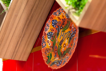 Colorful ceramic painted plates hanging on the red wall
