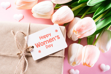 International Women's Day concept. Woman present, pink and white tulips with paper tag text on bright pink pastel background. flat lay, March 8.