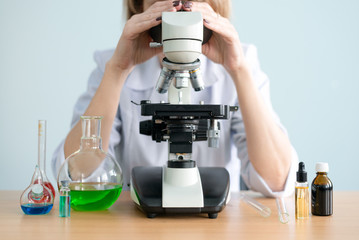 Scientist is looking through a microscope. Laboratory researching.