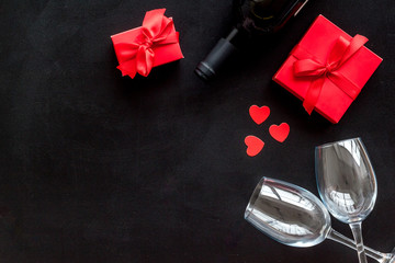Valentines Day concept with wine, glasses, red present box on black background top-down copy space