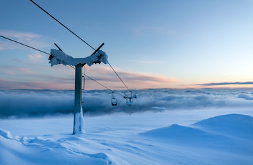 Cable car on the top of the snowy mountain, above she clouds Romania