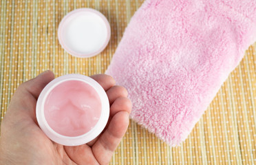 Woman holding a can with pink face cream in her hand