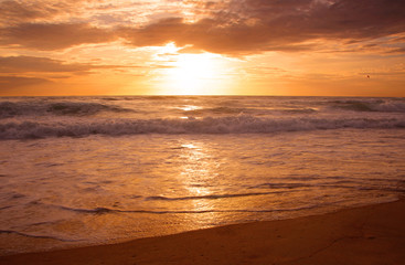 Beautiful sunset on tropical beach. The surf pounds the shore. Karon beach, Phuket, Thailand