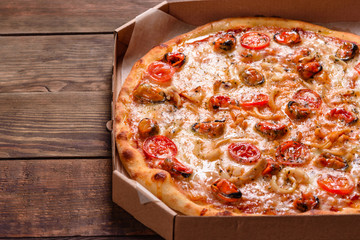 Tasty sliced pizza with seafood and tomato on a concrete background