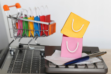 Paper shopping bag on Model miniature cart with calculator on computer keyboard, Shopping concept