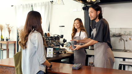 Zero waste concept, Asian woman customer giving her own coffee cup to barista, waiter, for buying takeout coffee at cafe counter
