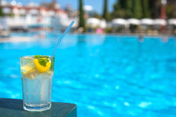 refreshing Mojito Cocktail at the edge of the resort's pool and lounge chairs for a relaxing luxury holiday Concept. Outdoor pool background