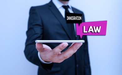 Writing note showing Immigration Law. Business concept for national statutes and legal precedents governing immigration Male human wear formal work suit hold smartphone using hand