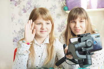 Two cute teenage girls are recording videos for their followers. Live broadcast, blog, greeting..