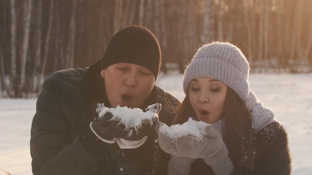 A couple blowing off the snow from their palms nin the woods