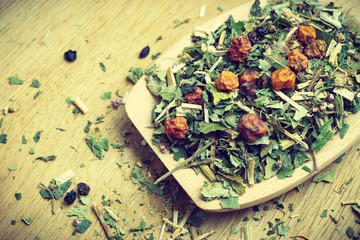 Pile of dry herb leaves and fruits on wooden spoon
