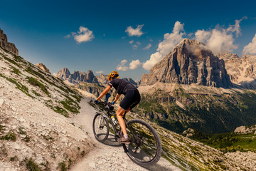 Fototapeta premium Cycling woman in Dolomites mountains landscape. Girl cycling MTB enduro trail track. Outdoor sport activity.